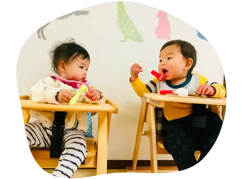 子供椅子に座って、おやつを楽しむ２人の子ども