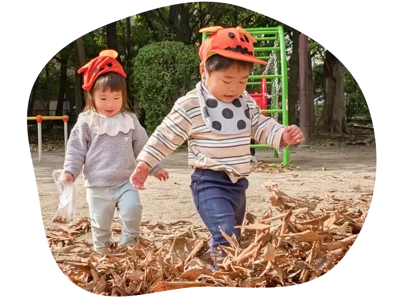 落ち葉が積もった公園で、楽しく遊んでいる２人の子ども