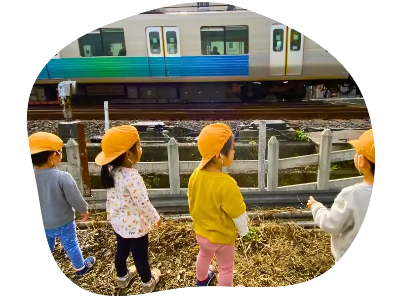 電車が通るのをわくわくしながら見ている4人の子どもたち